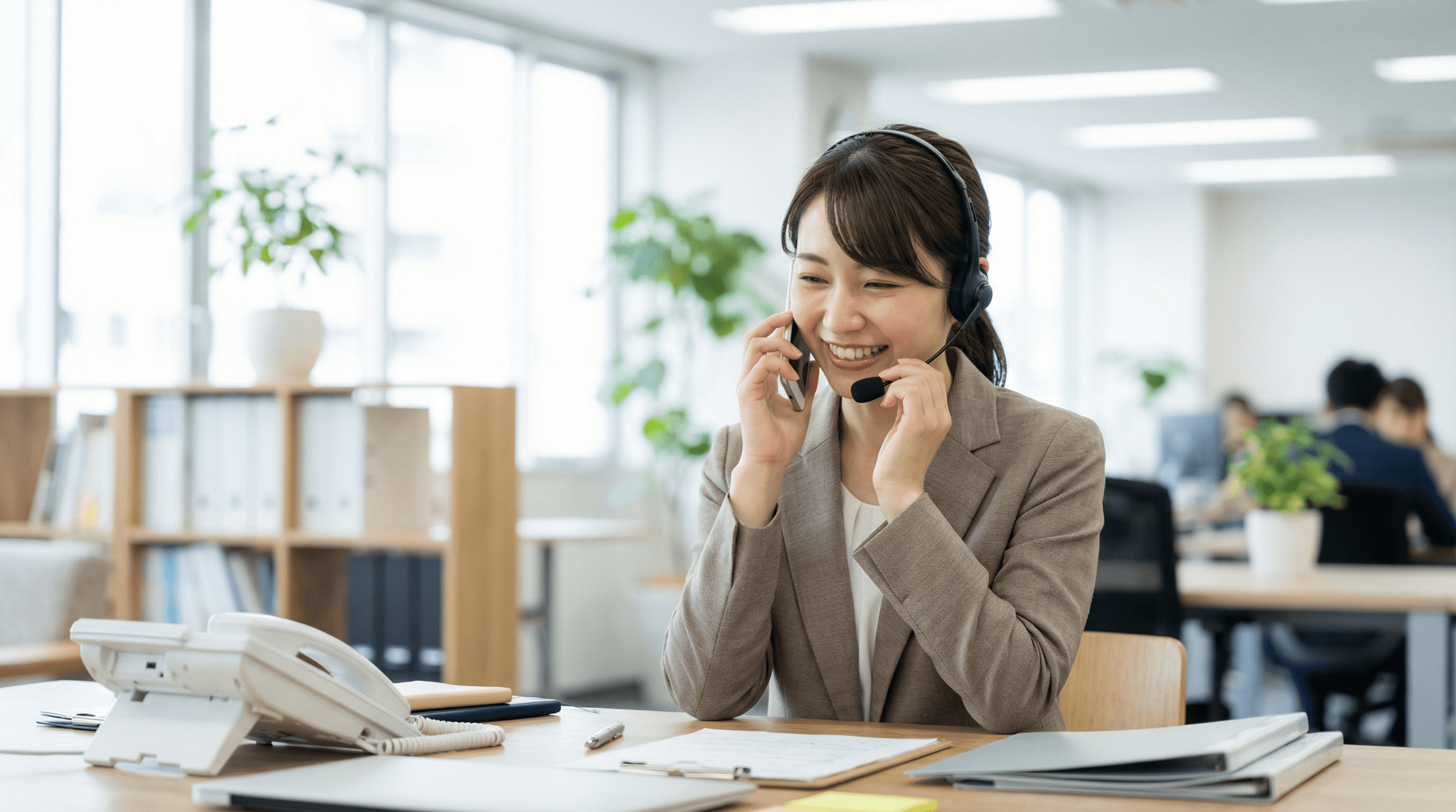 事務所でスタッフが笑顔で電話対応をしている写真